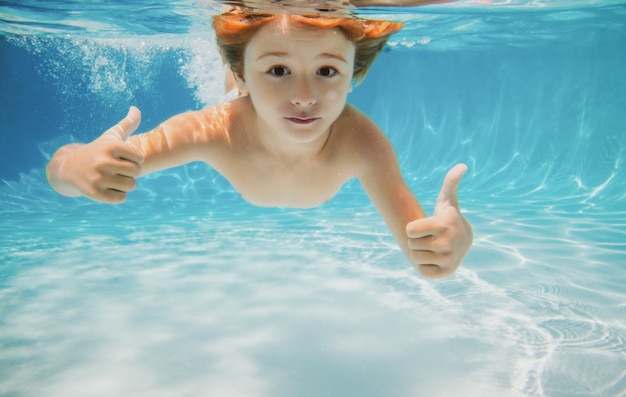 Child swims underwater in swimming pool happy active boy dives and has fun under water kids waterspo