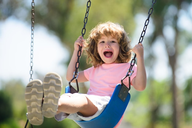 裏庭で子供がスイングするoudoorを遊んでいる子供幸せなかわいい男の子がスイングして楽しんでいる健康的な合計