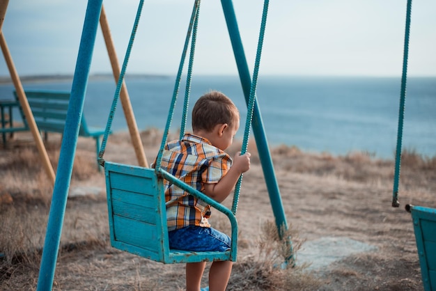 Foto bambino su un'altalena vicino al mare