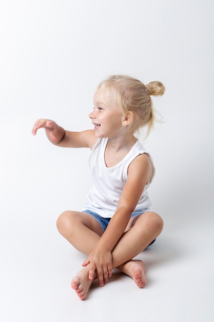 Child in a T-shirt, shorts sitting in the studio on a light background.