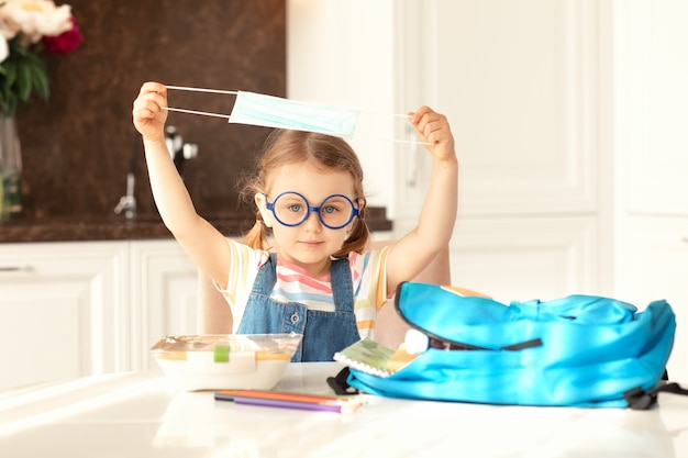 Child takes off protective mask get ready for school at home\
sunny morning kitchenback to school