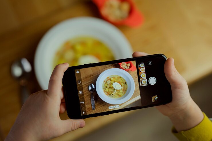 Photo 子供がスマートフォンで食べ物の写真を撮る