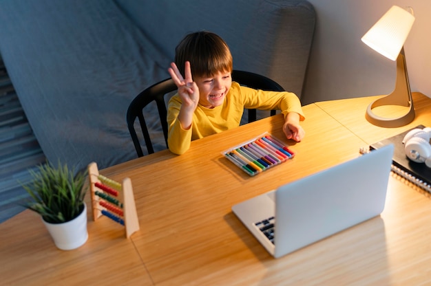 Photo child taking virtual courses and raising hand