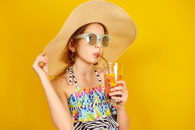 Child teenager girl in swimsuit straw hat and sunglasses with lemonade