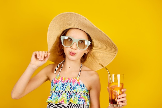 Child teenager girl in swimsuit straw hat and sunglasses with lemonade