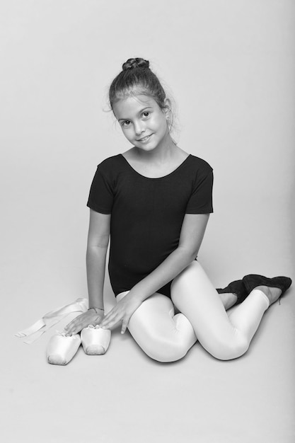 Child tender dancer look gorgeous fancy leotard Dream every girl become famous gymnast Kid sit hold pointe ballet shoes Special shoes for ballet Child flexible gymnast practice stretching tiptoes