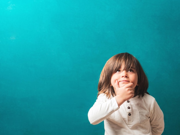 Child thinking in front of the blackboard