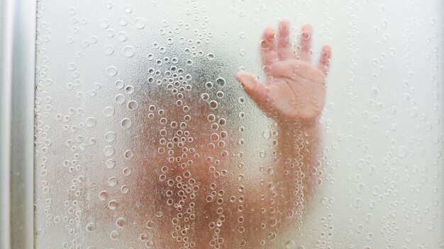 写真 バスルームのガラスに触れる子供