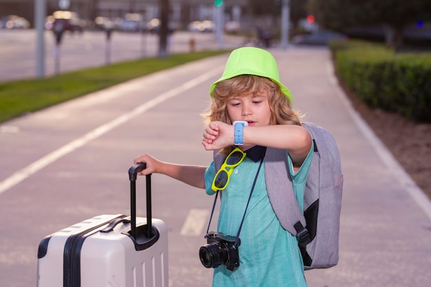 写真 荷物旅行バッグを持つ子供観光客 旅行 スーツケースを持つ子供 屋外の街の通りを歩く カジュアルな服を着た旅行者観光客の子供