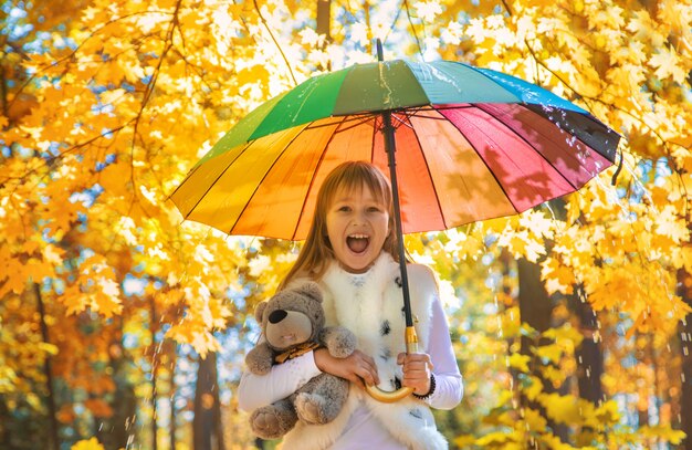 Child under an umbrella in the autumn park. Selective focus.