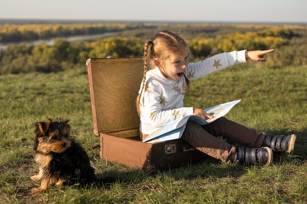 Photo child using a map and a dog sitting next to her