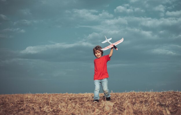 Child in the village with plane in his hands retro style airplane on nature background child boy tod