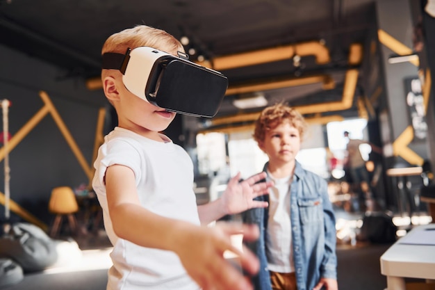 Il bambino con gli occhiali per realtà virtuale e in abiti casual si diverte nella stanza dei giochi