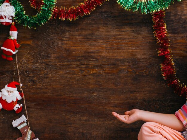 Child waiting for Christmas miracle Little girl pointing at wooden background with free space New Year artistic decoration festivity concept