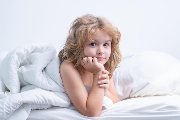 Child wakes up in the morning in the bedroom cute little boy waking up in bed