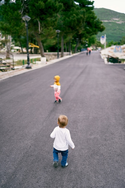 Photo child walks down the road and looks at another kid