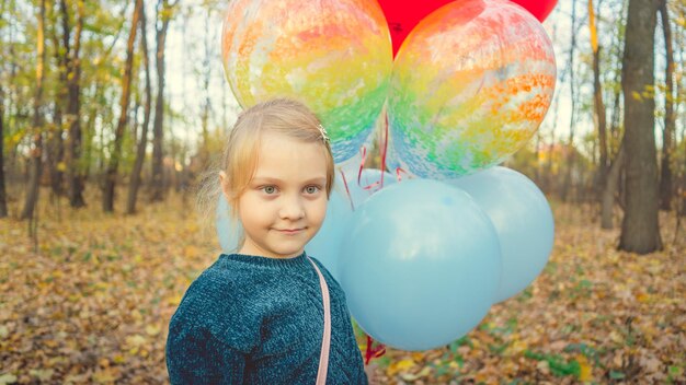 A child walks in the forest with a bunch of colored balls Girl holding colored balloons in her hand