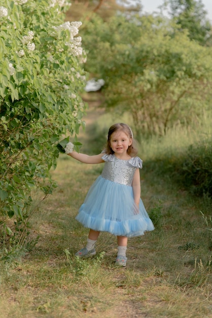 Child walks in the park little girl dressed in a blue dress