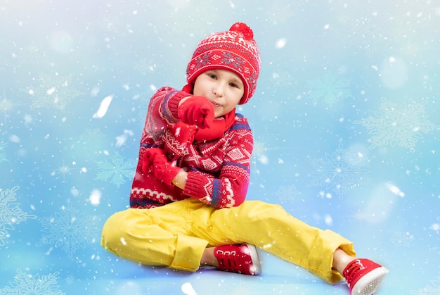 Child in warm clothes on a blue winter background