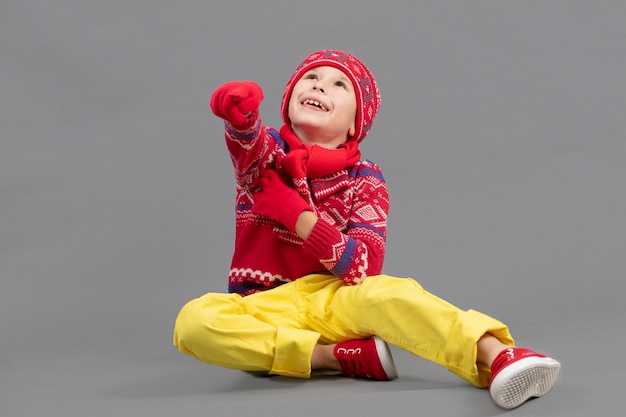 Child in warm knitted clothes on a studio background