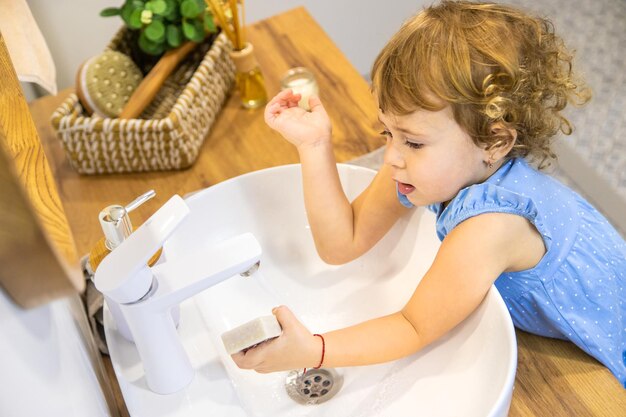 Photo the child washes his hands with soap selective focus