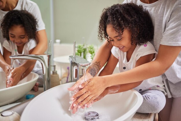 Child washing hands and family rinsing cleaning and good hygiene against bacteria or germs for infection or virus protection in bathroom Girl kid with woman mother for health care and cleanliness