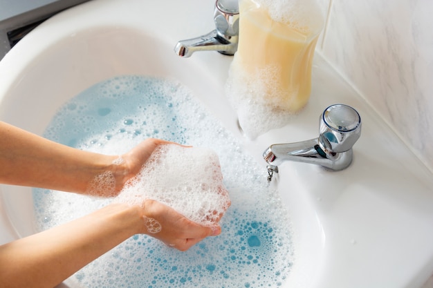 Child washing his hands over sink in bathroom.