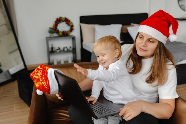 A child waves through a laptop camera on christmas eve communicating over the internet and online