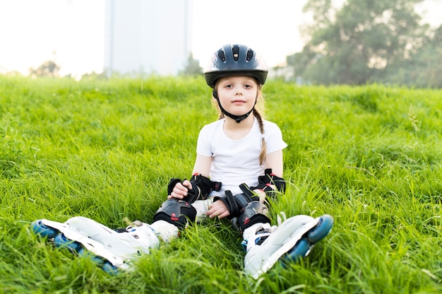 保護パッドと安全ヘルメットを身に着けている子供。公園で若いスケーター