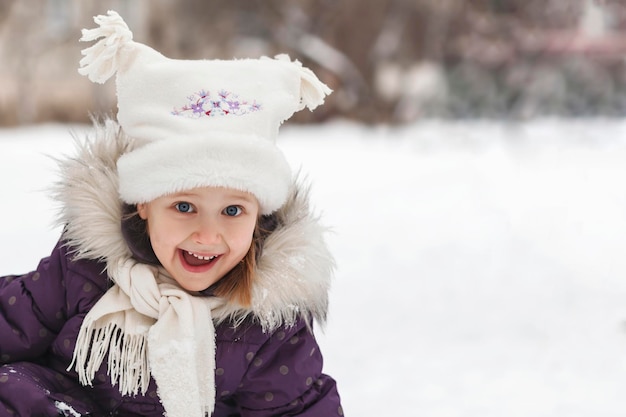 Child in winter clothes admiringly plays in the snow