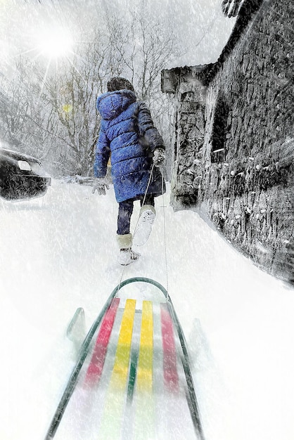 눈보라 속에서 겨울의 한 아이가 썰매를 끌고 걷는 창의적인 사진