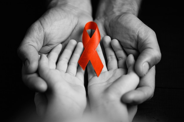 Child with AID red ribbon. the boy holds the symbol of the fight against HIV, AIDS. concept of helping those in need.black and white.