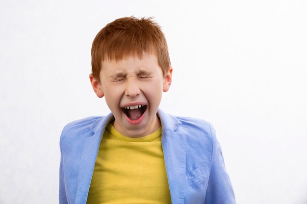 Photo child with an angry expression the boy screams and closed his eyes