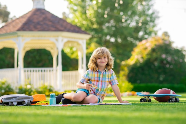 Photo child with artwork homework on playground kid boy create artist paints summer vacation school child