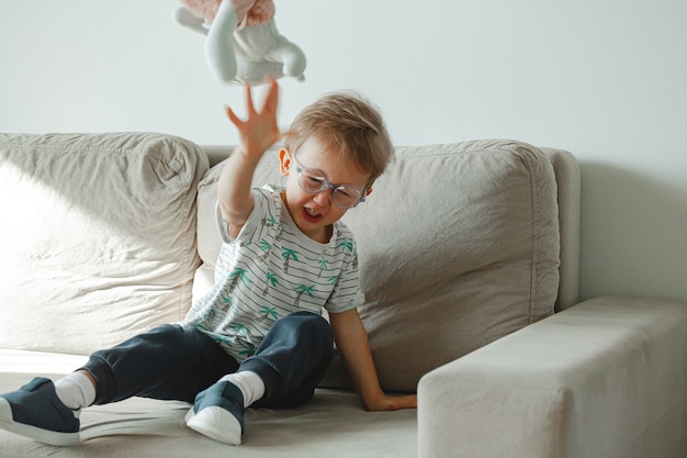 Un bambino con autismo con gli occhiali siede sul divano e triste, arrabbiato a