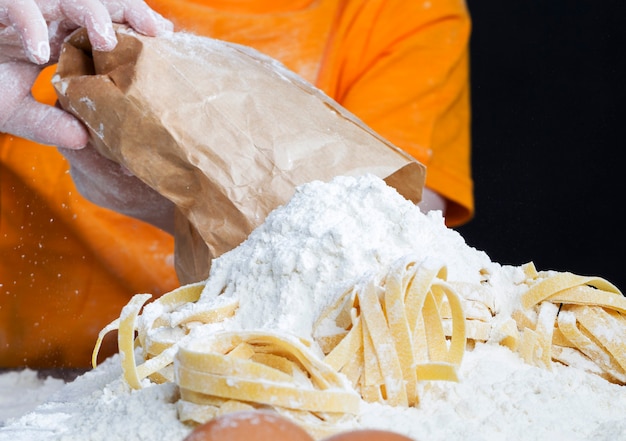 A child with a bag of flour and pasta with which he prepares food