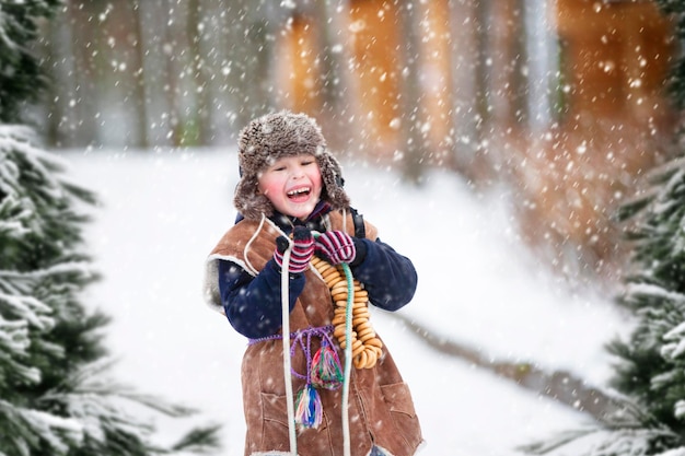 ベーグルを持つ子供が冬の背景にロープを引っ張る