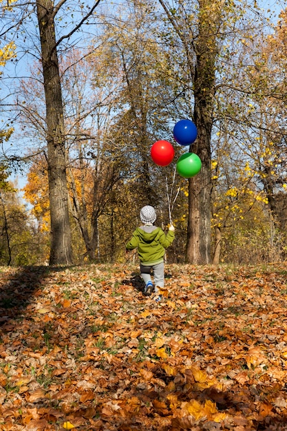 A child with balloons walking through the park