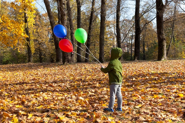 A child with balloons walking through the park