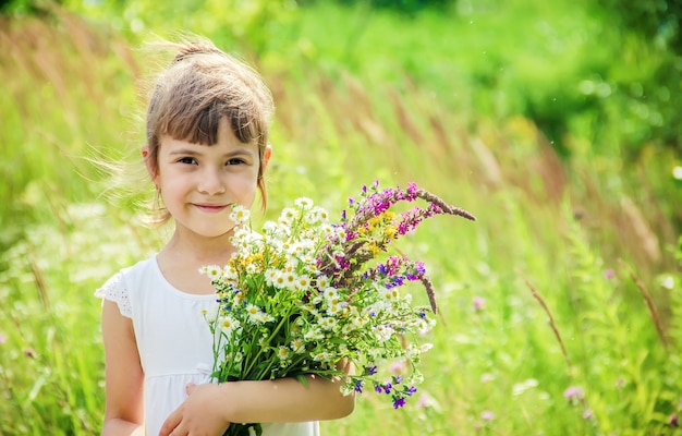 野生の花の花束を持つ子供。セレクティブフォーカス自然。