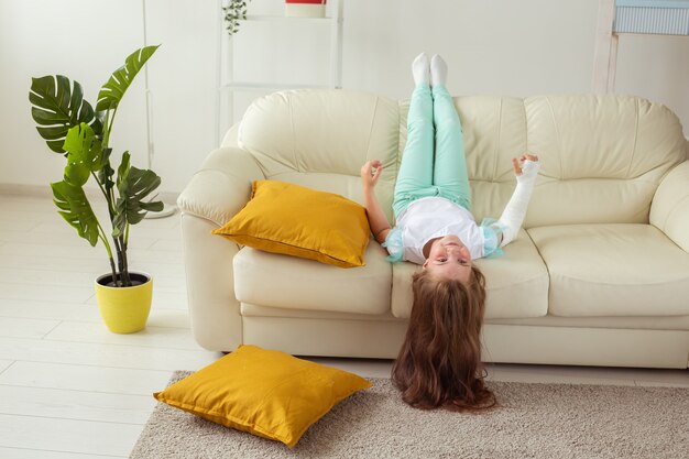 Child with a cast on a broken wrist or arm smiling and having\
fun on a couch positive attitude