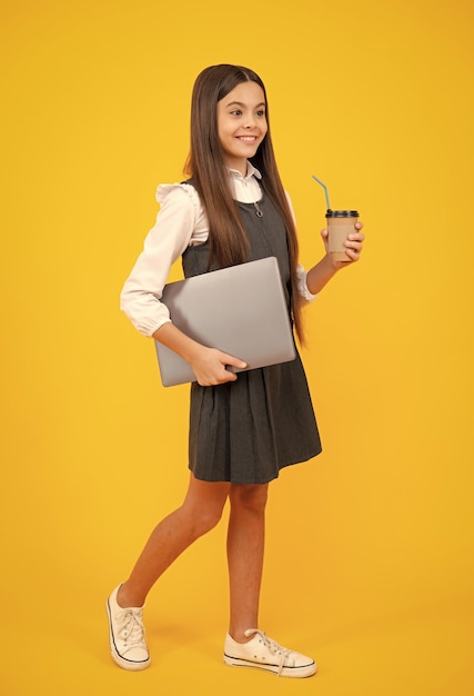 Child with coffee or tea cup isolated on yellow studio background Teenage girl with take away beverage