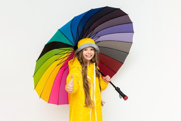 A child with a colorful umbrella in a yellow raincoat and a\
panama hat on a white isolated background