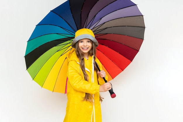 A child with a colorful umbrella in a yellow raincoat and a\
panama hat on a white isolated background