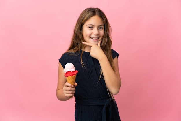 고립된 분홍색 배경 위에 코넷 아이스크림을 든 아이는 행복하고 웃고 있다