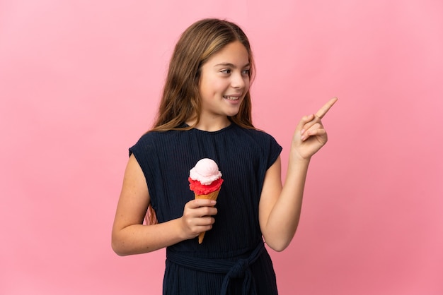 Child with a cornet ice cream over isolated pink pointing up a great idea