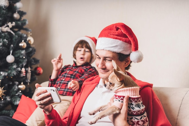 クリスマス休暇中に携帯電話でお父さんと子犬と子供