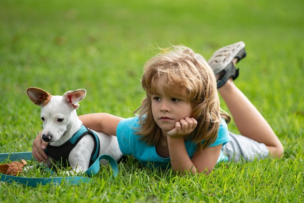 Photo child with a dog lying on backyard lawn kid relax with a puppy dog outdoor on grass at backyard lawn...