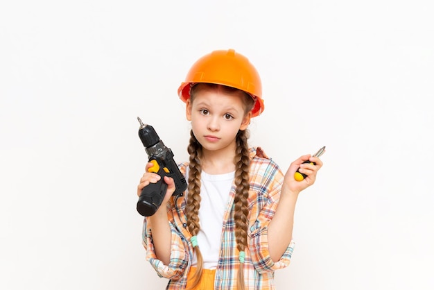 A child with a drill in his hands and wearing a protective construction helmetThe little girl wondered how to make repairs in the children's room The concept of repair