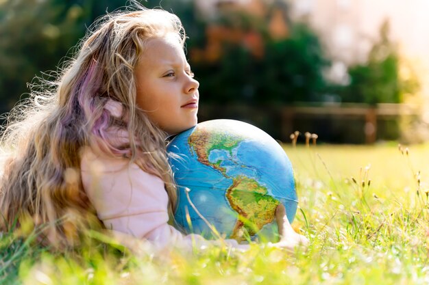 Child with earth globe portrait of a blonde european girl of elementary school with an educational g...